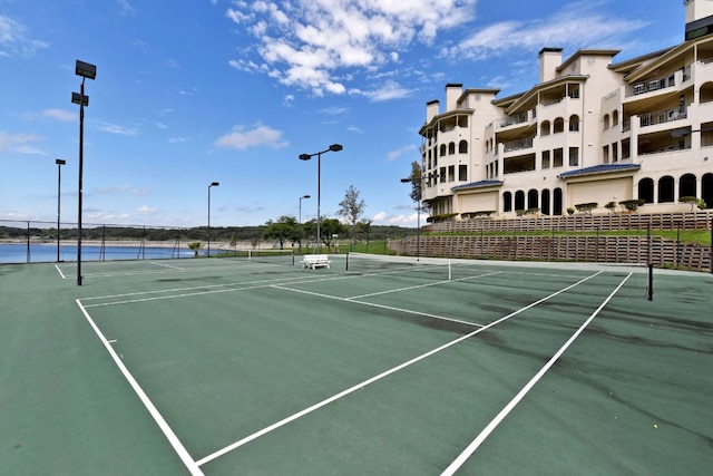 view of tennis court with community basketball court and fence