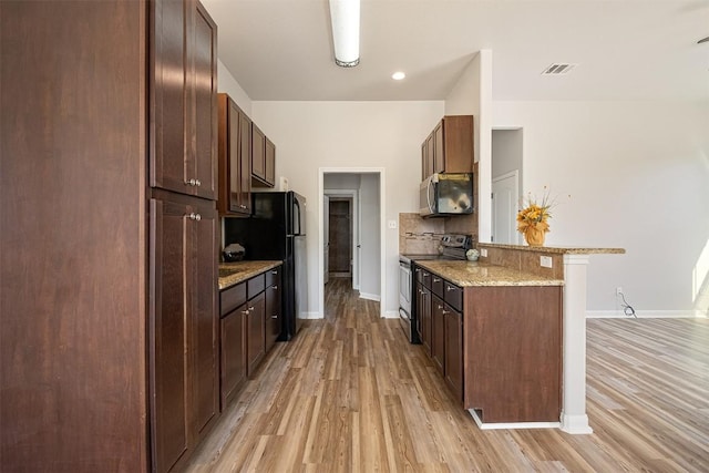 kitchen with light wood finished floors, baseboards, a peninsula, and appliances with stainless steel finishes