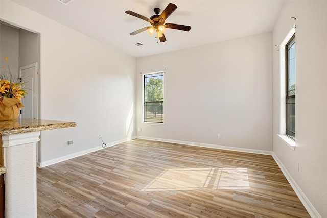 spare room with visible vents, light wood finished floors, ceiling fan, and baseboards