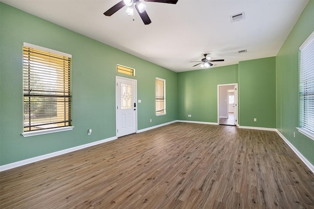 unfurnished living room with visible vents, baseboards, a ceiling fan, and wood finished floors