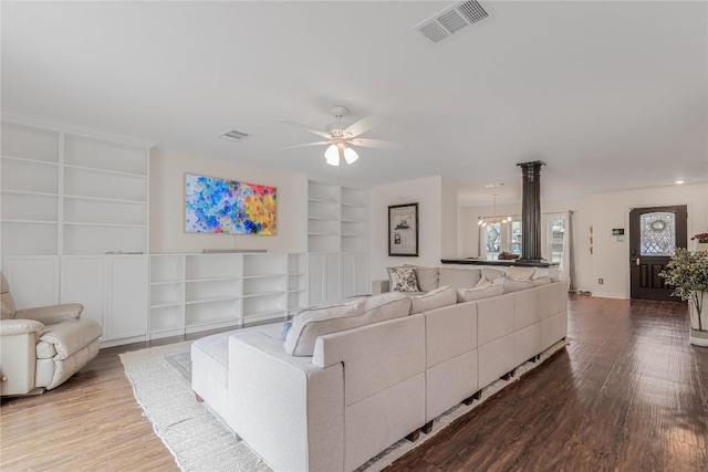 living room with built in shelves, wood finished floors, ceiling fan, and baseboards