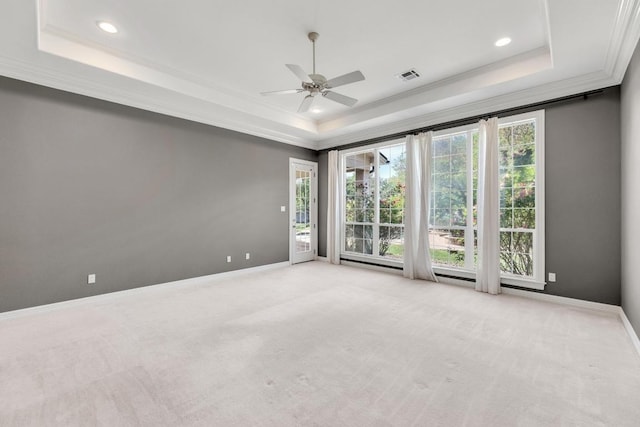 empty room featuring ornamental molding, visible vents, a raised ceiling, and a ceiling fan