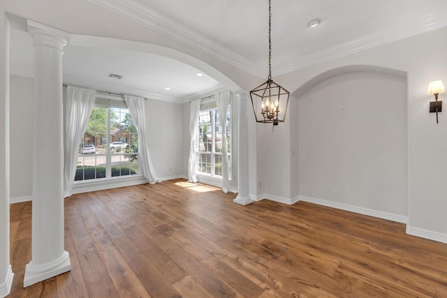 unfurnished dining area featuring crown molding, arched walkways, visible vents, wood-type flooring, and baseboards