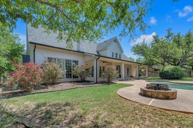 back of house featuring a lawn, a patio, an outdoor fire pit, and ceiling fan
