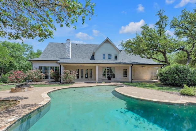 exterior space featuring a chimney, a patio area, a fire pit, french doors, and a shingled roof