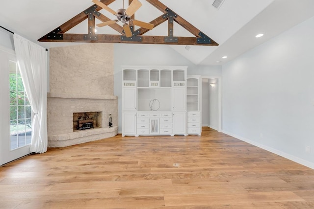 unfurnished living room with light wood-style floors, ceiling fan, a fireplace, and beam ceiling