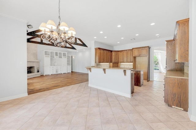 kitchen with ornamental molding, a chandelier, recessed lighting, open floor plan, and a breakfast bar area