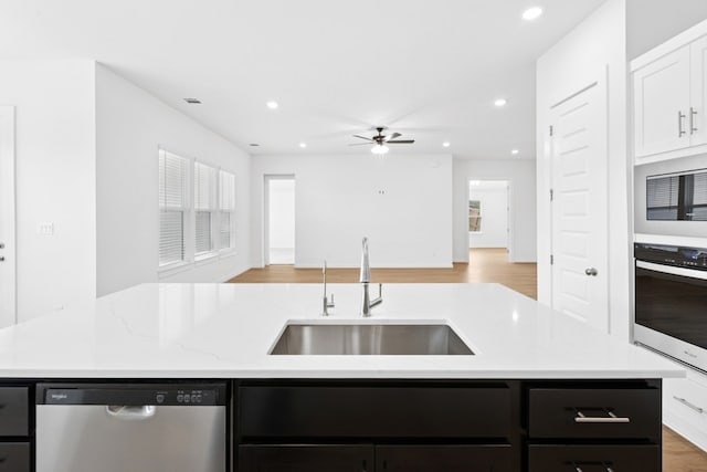 220 Washington Dr, Kyle, TX 78640 - kitchen with stainless steel appliances, dark cabinetry, a sink, open floor plan, and a ceiling fan