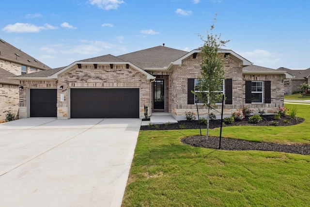 220 Washington Dr, Kyle, TX 78640 - view of front of property featuring an attached garage, driveway, a front lawn, brick siding, and a shingled roof