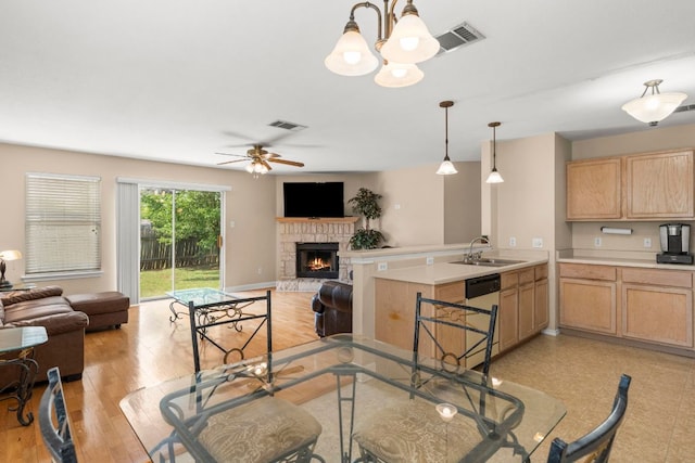 141 Sydneys Way, Buda, TX 78610 - dining area featuring a stone fireplace, a chandelier, a ceiling fan, and light wood-type flooring