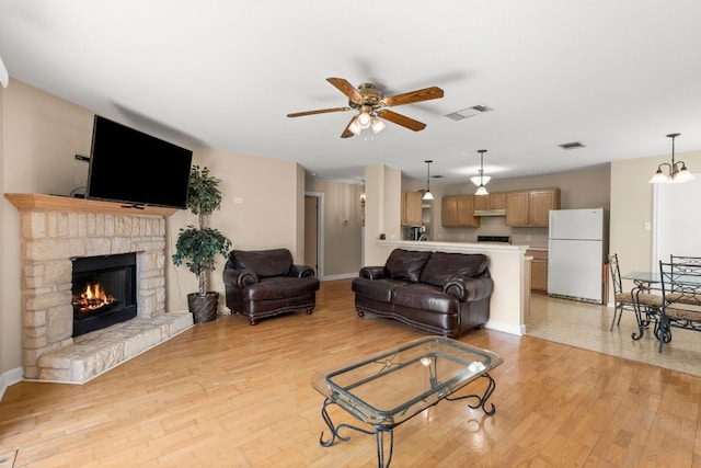 141 Sydneys Way, Buda, TX 78610 - living room featuring a ceiling fan, light wood-type flooring, and a stone fireplace