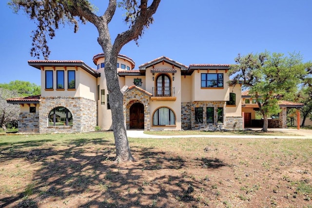 mediterranean / spanish home with french doors, stucco siding, stone siding, and a tile roof