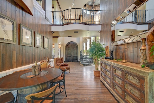 interior space featuring wood walls, wood finished floors, arched walkways, and a towering ceiling