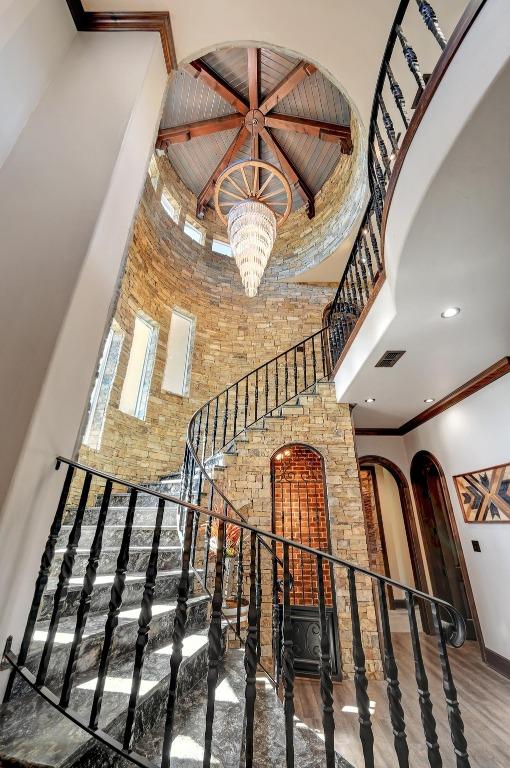 stairs featuring a chandelier, arched walkways, a high ceiling, and visible vents