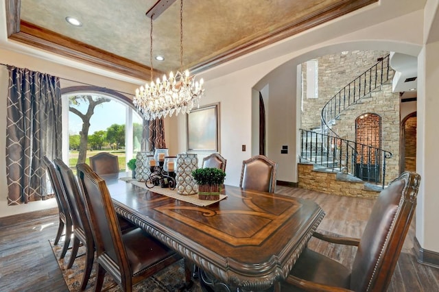 dining space with crown molding, stairs, a tray ceiling, arched walkways, and wood finished floors