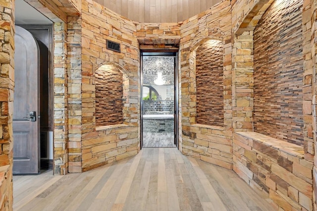 corridor featuring arched walkways, visible vents, wooden ceiling, and wood finished floors