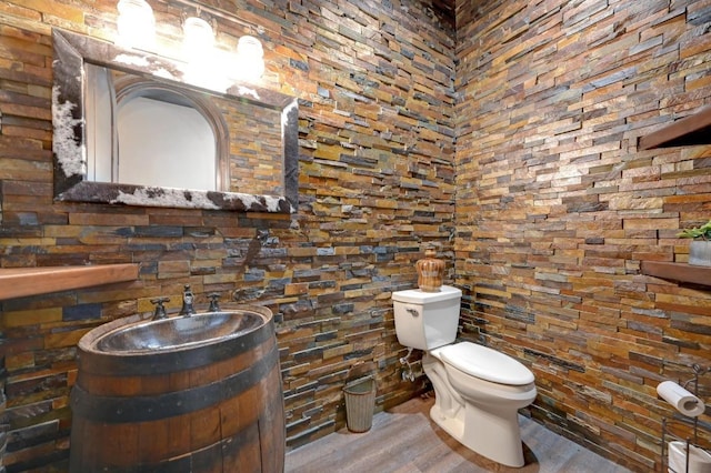 half bath with toilet, vanity, and wood finished floors