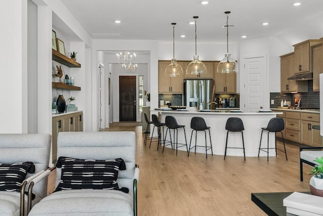 400 Veneta Ln, Georgetown, TX 78633 - kitchen with stainless steel refrigerator with ice dispenser, under cabinet range hood, a kitchen bar, decorative backsplash, and recessed lighting