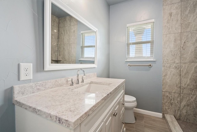 bathroom featuring toilet, vanity, and baseboards