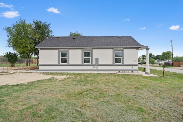 view of front of home featuring a front lawn, stucco siding, and roof with shingles