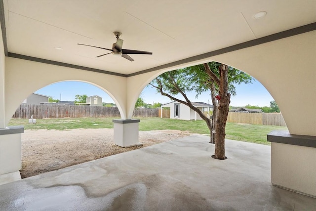 view of patio with an outbuilding, ceiling fan, and a fenced backyard