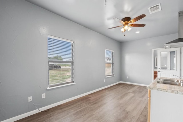 unfurnished bedroom with a sink, visible vents, baseboards, and light wood-type flooring