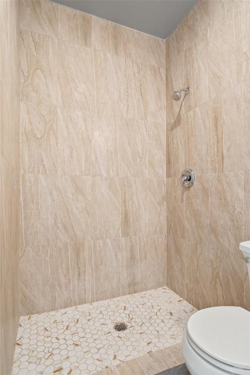 bathroom featuring toilet and a tile shower
