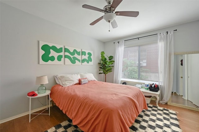 bedroom with wood finished floors, a ceiling fan, and baseboards