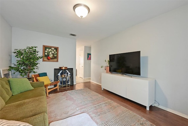 living area with baseboards, wood finished floors, and visible vents
