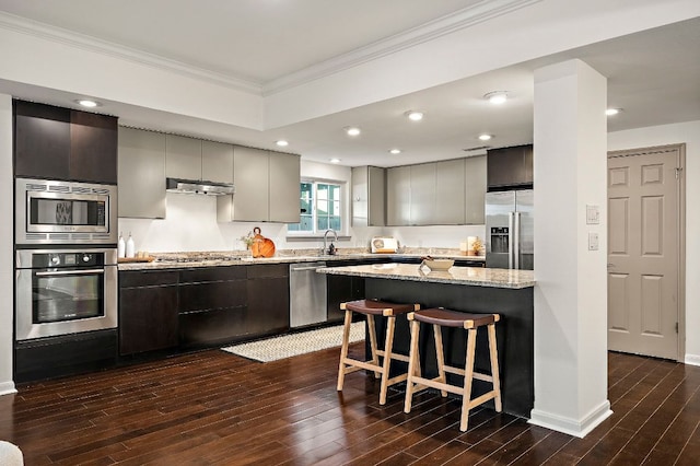1702 Newning Ave Unit B, Austin, TX 78704 - kitchen featuring stainless steel appliances, extractor fan, crown molding, dark wood-type flooring, and a kitchen bar