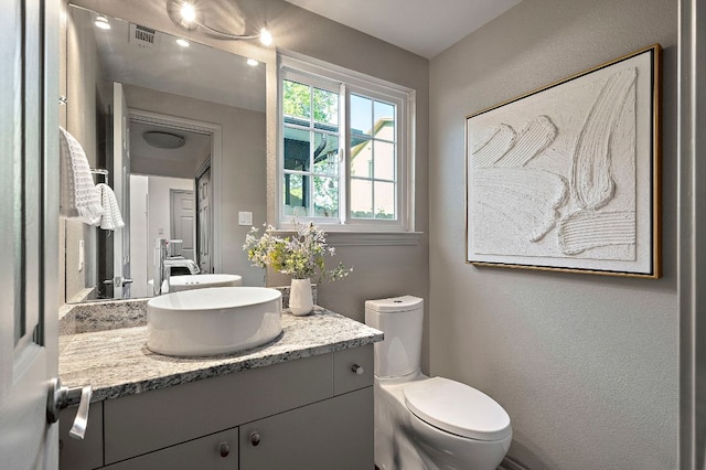 bathroom featuring toilet, vanity, and visible vents