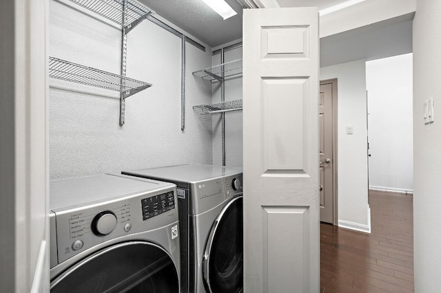 clothes washing area featuring baseboards, washer and dryer, dark wood-style flooring, and laundry area