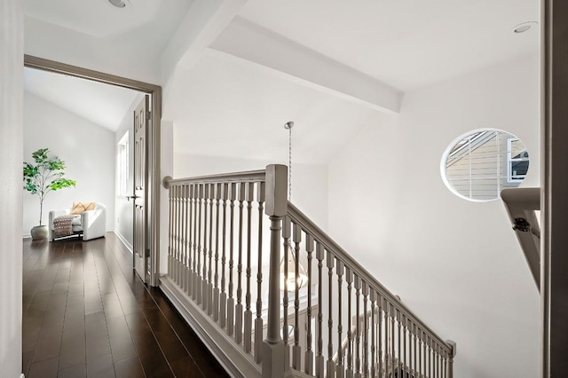 hall featuring dark wood-type flooring, lofted ceiling with beams, and an upstairs landing