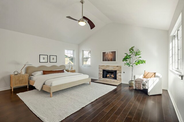 bedroom featuring high vaulted ceiling, dark wood-type flooring, a ceiling fan, a stone fireplace, and baseboards
