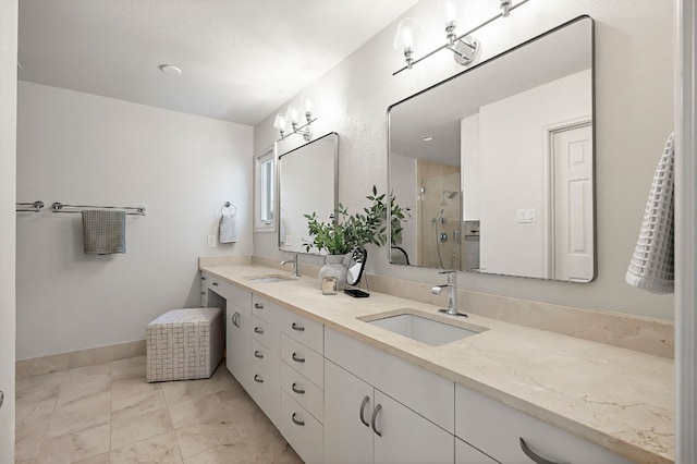full bath with double vanity, baseboards, a sink, and a stall shower