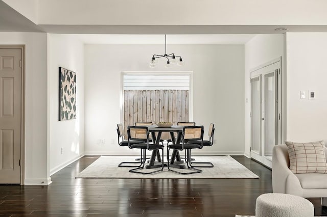 dining space featuring baseboards, a healthy amount of sunlight, a notable chandelier, and dark wood-style floors