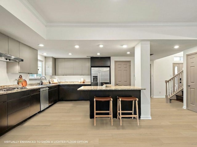 1702 Newning Ave Unit B, Austin, TX 78704 - kitchen with appliances with stainless steel finishes, ornamental molding, a breakfast bar area, light wood finished floors, and light stone counters