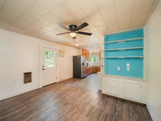 unfurnished living room with a ceiling fan, dark wood-style floors, and a wealth of natural light