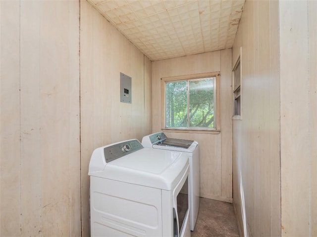 clothes washing area with wooden walls, washing machine and clothes dryer, and laundry area
