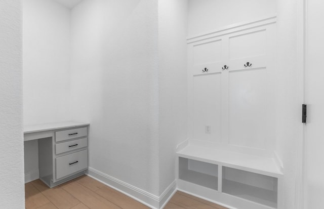 mudroom featuring baseboards, built in study area, and light wood finished floors