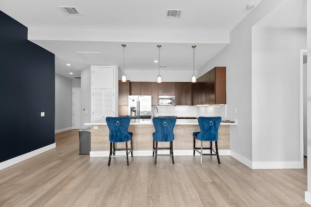 507 Sabine St Unit 505, Austin, TX 78701 - kitchen with appliances with stainless steel finishes, a breakfast bar area, light wood-style floors, a peninsula, and recessed lighting