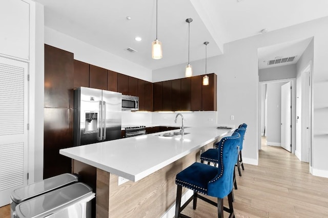 507 Sabine St Unit 505, Austin, TX 78701 - kitchen featuring appliances with stainless steel finishes, a breakfast bar, light wood-style floors, light countertops, and dark brown cabinetry