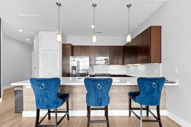 507 Sabine St Unit 505, Austin, TX 78701 - kitchen with stainless steel appliances, a breakfast bar, light wood-style flooring, light countertops, and recessed lighting