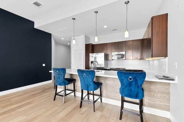 507 Sabine St Unit 505, Austin, TX 78701 - kitchen with stainless steel appliances, light wood-style floors, a kitchen breakfast bar, pendant lighting, and recessed lighting
