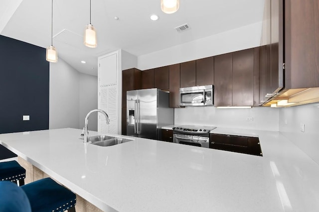 507 Sabine St Unit 505, Austin, TX 78701 - kitchen with appliances with stainless steel finishes, light countertops, dark brown cabinetry, hanging light fixtures, and a peninsula