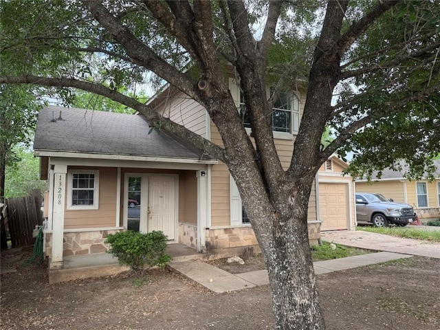 view of front facade featuring fence, an attached garage, a shingled roof, and concrete driveway