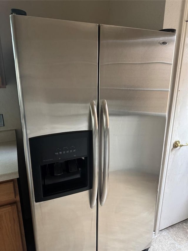 details with brown cabinets, stainless steel fridge, and light countertops