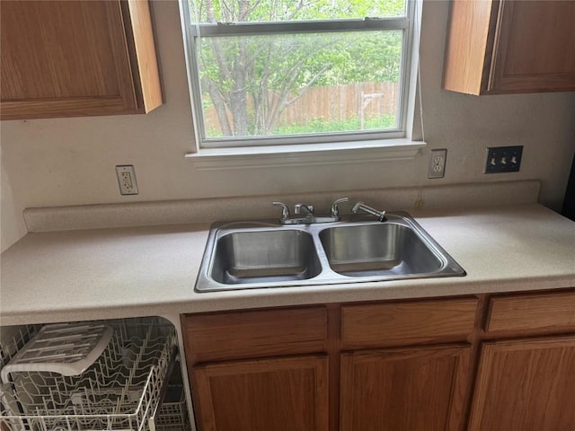 kitchen with light countertops, brown cabinetry, a wealth of natural light, and a sink