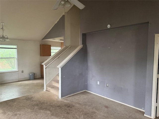 unfurnished living room featuring stairway, vaulted ceiling, carpet floors, baseboards, and ceiling fan with notable chandelier