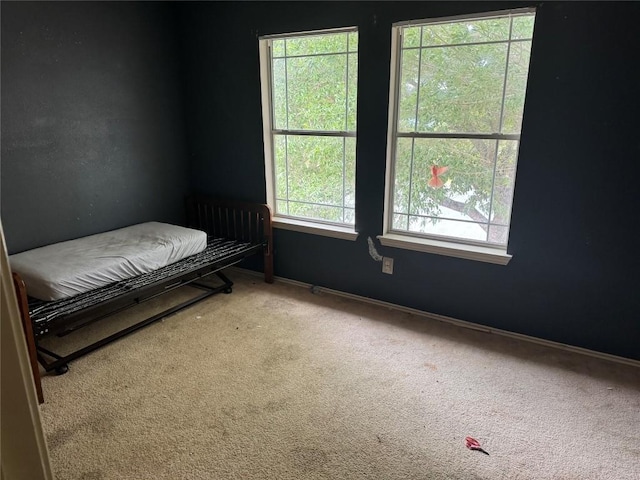 carpeted bedroom featuring baseboards and multiple windows
